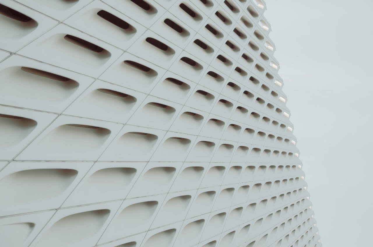 about-img Abstract view of a white geometric building facade with grid pattern design.